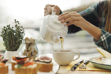 从茶壶中倒茶的女人的特写视角