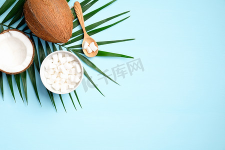 扁平的椰子树和热带棕榈叶组成蓝色背景.健康饮食或有机SPA化妆品的概念.夏季背景.