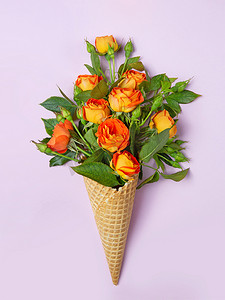 花束包装摄影照片_新鲜的黄色橙色玫瑰在一个松饼锥粉红色的背景。复制空间，平铺。花束的原始包装.
