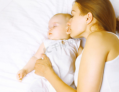 婴儿期摄影照片_妈妈和宝宝睡在床上，婴儿期，孕产和和谐 co