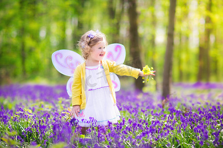 蓝铃花林中仙女装束蹒跚学步的女孩