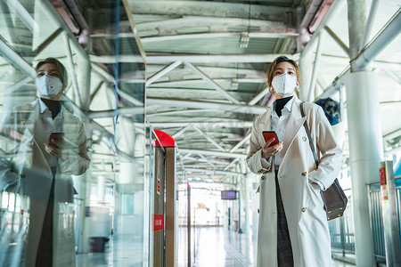 戴口罩的年轻女人站在地铁站台上