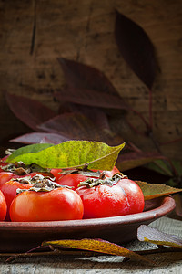 Ripe persimmons with leaves on a clay plate 