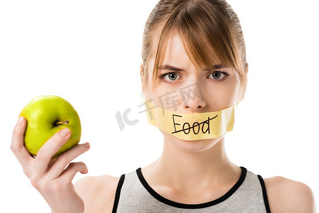 藏品摄影照片_年轻女子用棍子带打通过词食物覆盖嘴藏品苹果在白色隔绝了