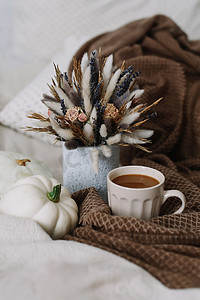 南瓜花摄影照片_咖啡杯，花和南瓜放在舒适的格子花上。 秋天的平静生活。 早餐在床上。 -早上好 别致的秋色平平平静静. 