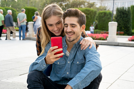 在社交媒体上，这对年轻夫妇使用智能手机应用在网上博客上发表评论。 年轻男女在社交网络上与家人和朋友们分享照片.