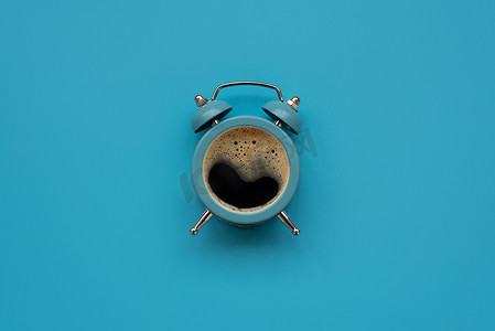 闹钟如蓝色背景的咖啡杯. 顶部视图。 平躺在床上 早上好，概念