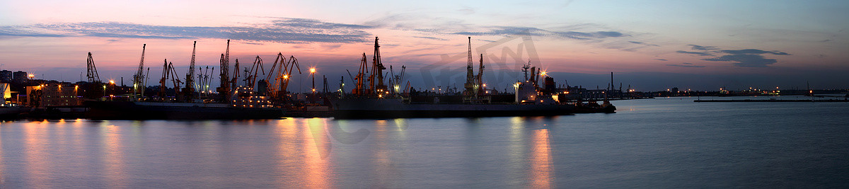 几个起重机在港口，在日落时分拍摄剪影