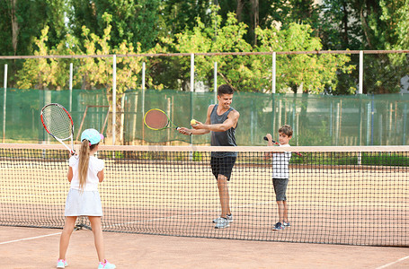 小孩子在球场上打网球的年轻教练