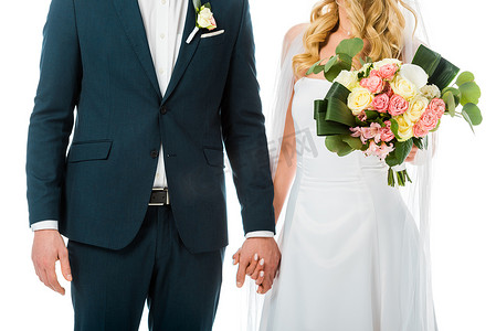 裁剪的新娘的看法与美丽的婚礼花束牵手与新郎在优雅的西装孤立在白色