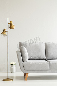 金色的台灯和花朵旁边的灰色沙发在典雅明亮的客厅内饰