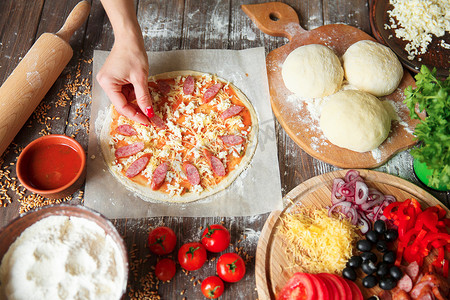 在厨房里烹调,把配料放在披萨上.比萨的概念。粮食生产和交付