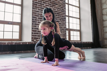 健身的小女孩摄影照片_微笑儿童健身教练的指导工作与展示如何做木板运动健身工作室中的小女孩