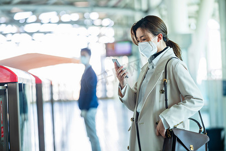 地铁戴口罩摄影照片_戴口罩的年轻女人站在地铁站台上