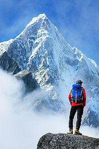 背着背包徒步旅行者到达山峰的峰会。成功的自由和幸福成就在山中。活跃的运动概念.