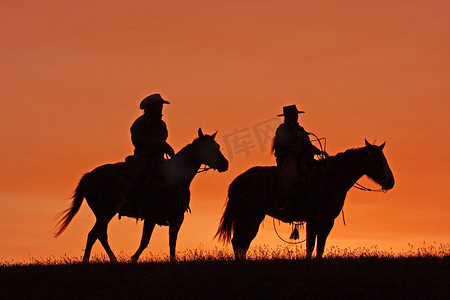 牛仔在日落时骑马剪影