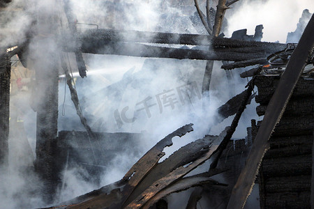 大火。废墟和烧毁的木结构房屋的遗迹。在浓烟中烧焦的柴火.