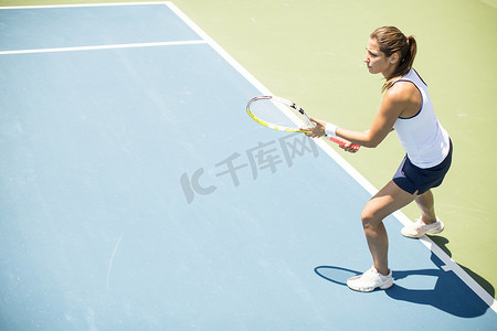 晴朗的一天摄影照片_年轻漂亮的女人，在晴朗的一天打网球