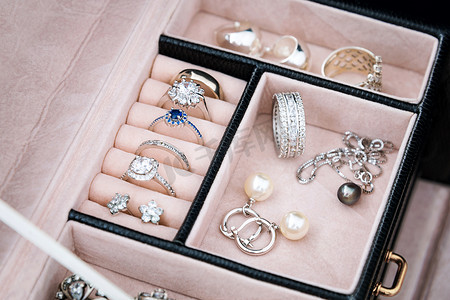 银耳环摄影照片_与白色黄金和银戒指，耳环，吊坠与珍珠珠宝盒。奢华珠宝的集合.