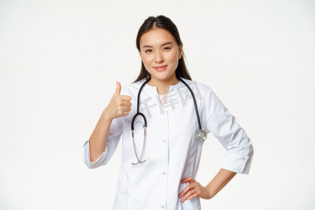 穿着医疗制服的专业医生微笑着露出大拇指.快乐的亚洲女医生证实了口臭，推荐产品，白色背景