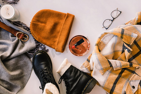 Stylish warm closes and accessories, top view. Leather boots, checkered warm shirt, knitted hat and other items on the white background, top view