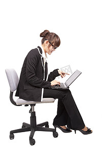 在椅子上使用便携式计算机的商界女强人