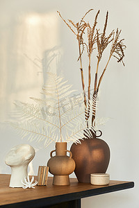 木制桌子上用干花、书和装饰的设计花瓶装饰着风格别致的构图。墙上美丽的影子。摘要概念在现代室内环境中的应用.模板.