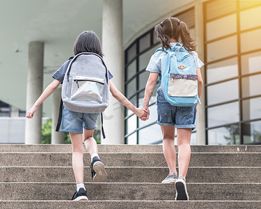 回到学校教育的概念，让女童（小学生）提着背包，手牵手走上校园楼梯间，快乐地走到一起