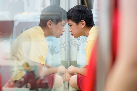 男孩郁闷摄影照片_靠近窗户的不安的男孩