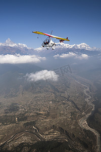 三轮车摄影照片_在尼泊尔的博克拉和布尔纳地区, 超轻型飞机和三轮车飞过。Machapuchare 峰会