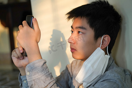 微信微信摄影照片_戴口罩的男孩看手机