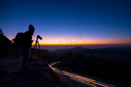 剪影专业摄影师与照相机采取风景相片在黄昏日出