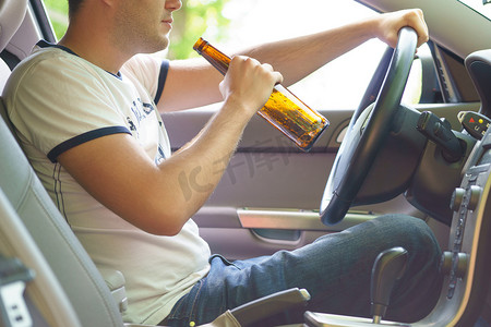 喝啤酒摄影照片_人在驾驶汽车时喝啤酒.