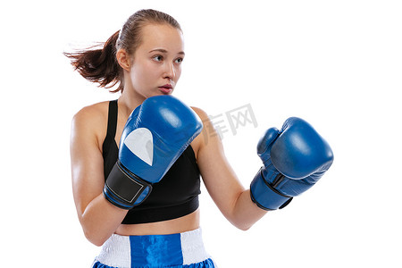 学习行动摄影照片_在行动中，运动。年轻的女孩，职业拳击手在拳击手套练习隔离的白色工作室背景。体育、学习、竞赛的概念