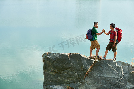 攀登高山摄影照片_快乐的朋友与大背包握手后攀登高山 