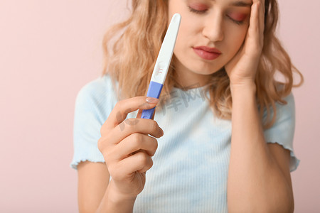 在肤色背景、特写镜头下进行怀孕测试的悲伤年轻女性