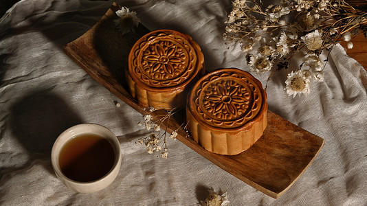 dried摄影照片_Moon cake for Mid autumn festival , Chinese traditional food and dessert decorating with dried flower on wooden table.