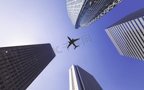 虚线小飞机摄影照片_飞机在高楼大厦之间飞行