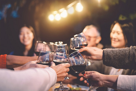 Happy family cheering with red wine at reunion dinner in garden - Senior having fun toasting wineglasses and dining together outdoor - People and food lifestyle concept