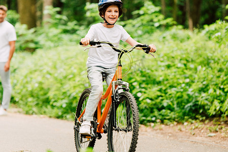 选择的焦点快乐男孩骑自行车，而父亲站在看儿子 
