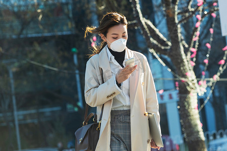 戴口罩的青年女人看手机