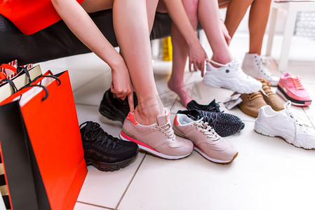 特写照片的女性腿选择运动鞋试穿不同的运动鞋，在商场里
