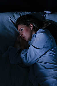 睡眠障碍，失眠。年轻的金发女人躺在床上醒着