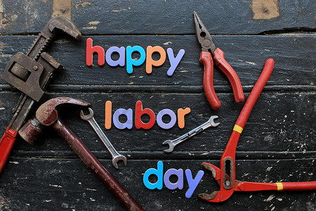 劳动节快乐文字在木制背景上的红色建筑维修工具。劳动节概念标志.快乐的工作日-写作螺丝.