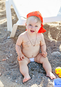 cute摄影照片_Cute little girl sitting on the sand and plays