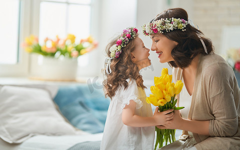 祝贺摄影照片_母亲节快乐！孩子们祝贺妈妈。妈妈和女儿笑着拥抱着。家庭假日和团聚.