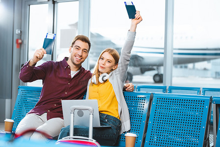 幸福的女朋友拿着护照以上的头靠近微笑的男友在机场附近的行李 