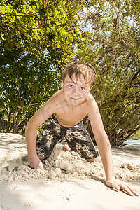 快乐的小男孩挖沙子的海滩 