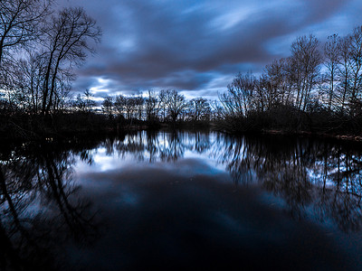 以上摄影照片_梦幻般美丽的长曝光日落照片与蓝色和粉红色的云以上与镜像反射的树木和天空在平静的水中的一个池塘在威斯康星州做一个华丽的背景.
