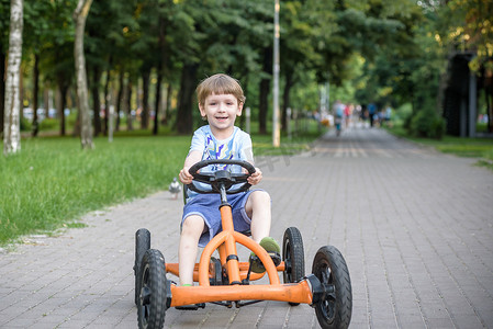 开心驾驶摄影照片_学龄前的小男孩驾驶大玩具跑车和在户外玩得开心，.